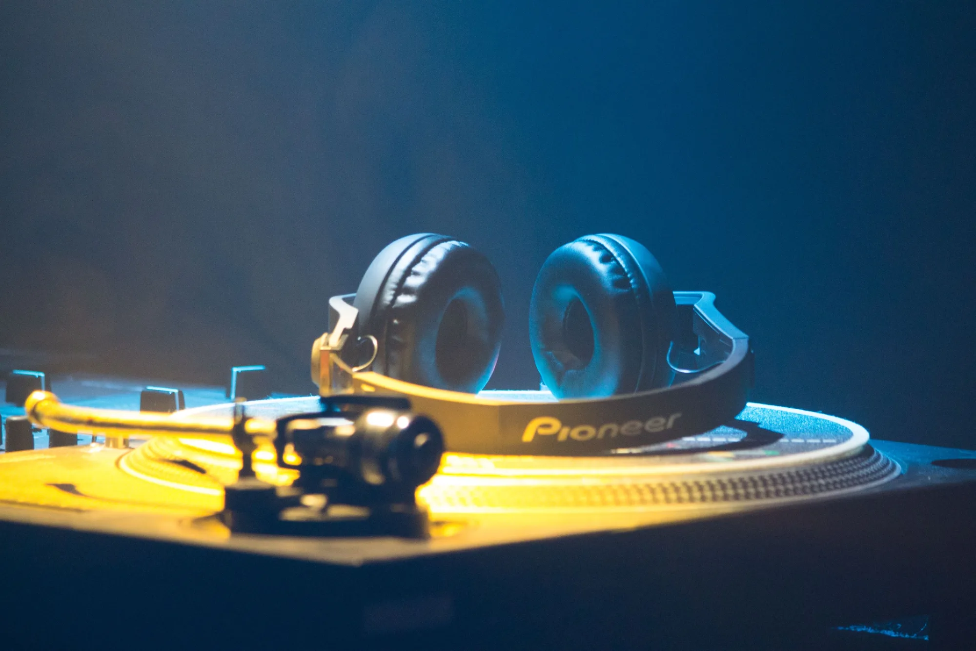 Professional DJ headphones resting on a turntable under vibrant blue and yellow neon lights, capturing Leeds' energetic nightlife and live music scene.